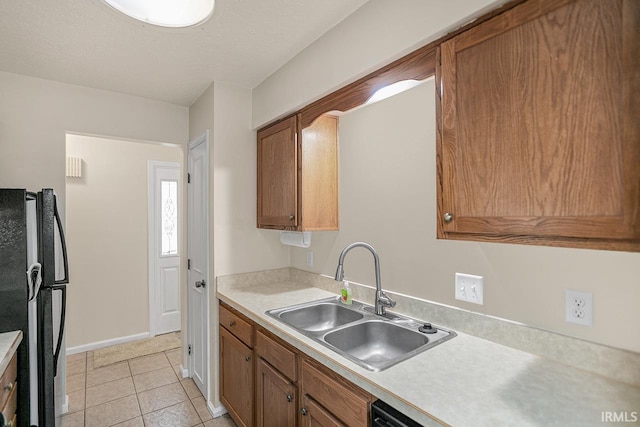 kitchen with black refrigerator, light tile patterned floors, and sink