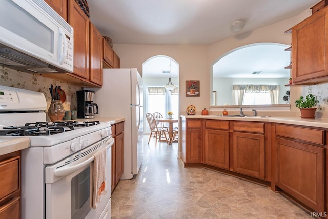 kitchen with white appliances, decorative light fixtures, and sink