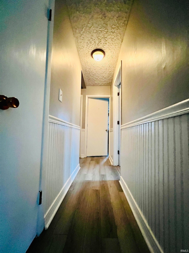 hallway featuring wood-type flooring and a textured ceiling