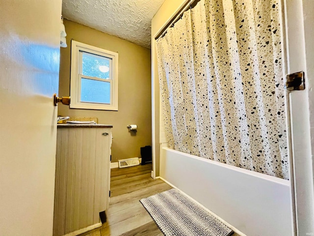 bathroom featuring shower / tub combo, a textured ceiling, and hardwood / wood-style flooring