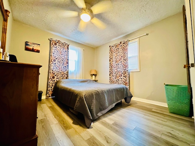 bedroom featuring ceiling fan, light wood-type flooring, and a textured ceiling