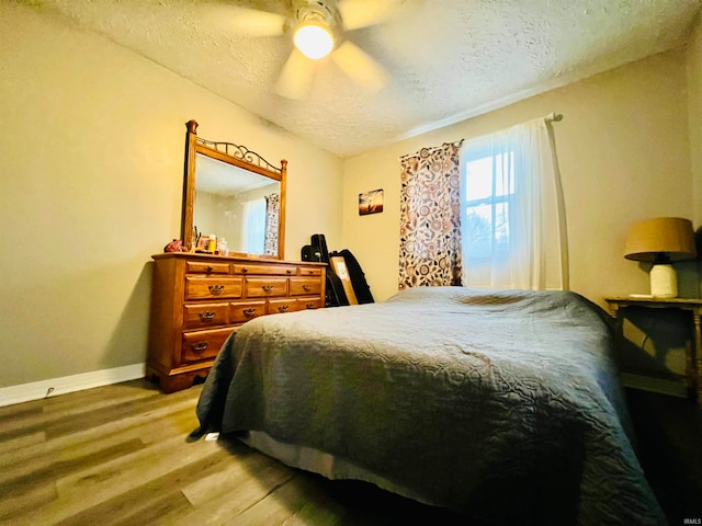 bedroom featuring ceiling fan, hardwood / wood-style floors, and a textured ceiling