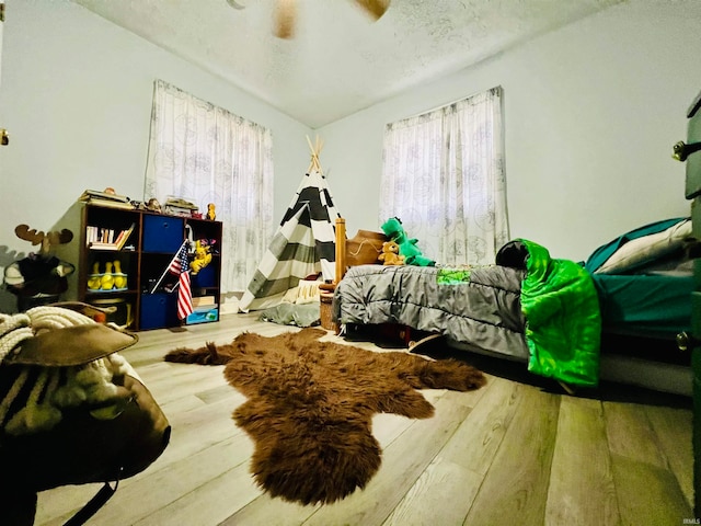 bedroom featuring ceiling fan, wood-type flooring, and a textured ceiling