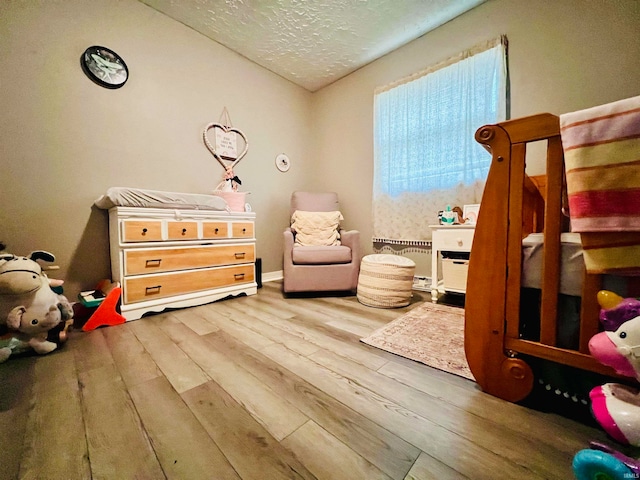 bedroom with hardwood / wood-style flooring, a textured ceiling, and vaulted ceiling