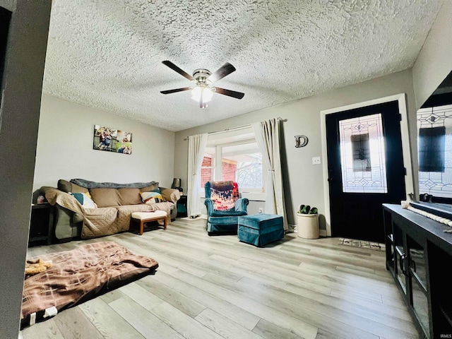 living room with ceiling fan, a textured ceiling, and light wood-type flooring