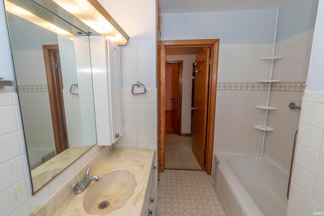 bathroom with vanity, a tub to relax in, and tile walls