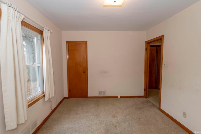 spare room featuring light colored carpet and plenty of natural light