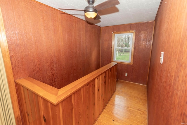 hall with wood walls and light hardwood / wood-style floors