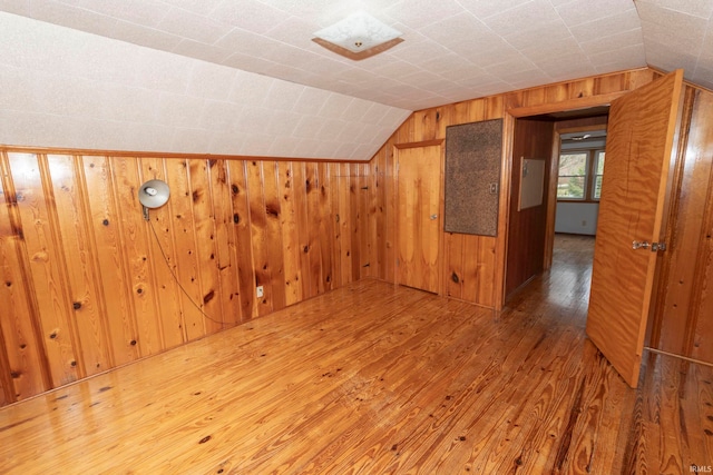 bonus room featuring wood walls, wood-type flooring, and lofted ceiling