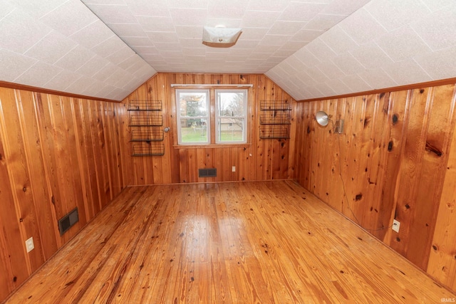 bonus room featuring lofted ceiling, wood walls, and light hardwood / wood-style floors