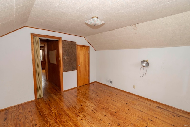 additional living space featuring hardwood / wood-style flooring and lofted ceiling