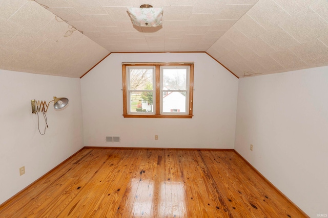 bonus room with light hardwood / wood-style floors and lofted ceiling