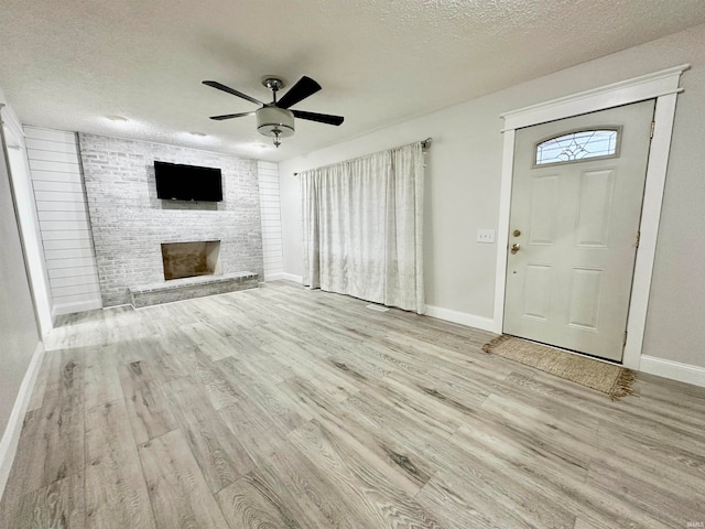 interior space with a fireplace, light hardwood / wood-style floors, a textured ceiling, and ceiling fan