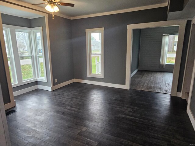 empty room featuring crown molding, a wealth of natural light, dark wood-type flooring, and ceiling fan