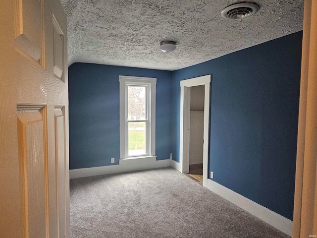 spare room with a textured ceiling, carpet floors, and lofted ceiling