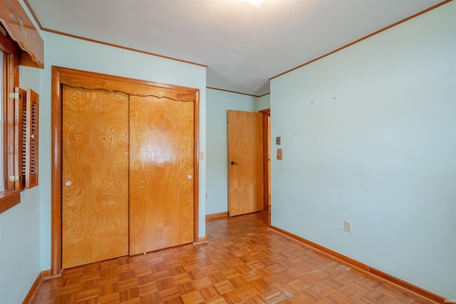 unfurnished bedroom with a closet, crown molding, and light parquet floors