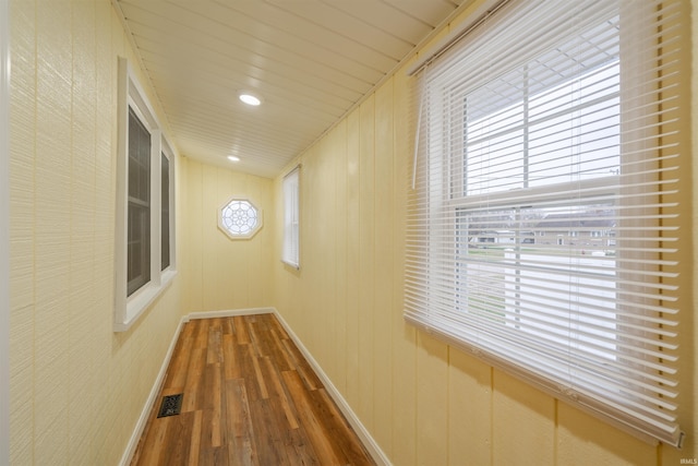 hallway with hardwood / wood-style floors, a healthy amount of sunlight, wooden ceiling, and wooden walls