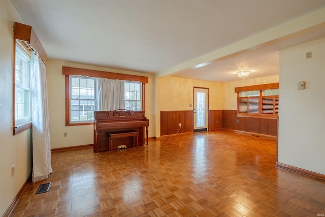 unfurnished living room with light parquet floors and wood walls