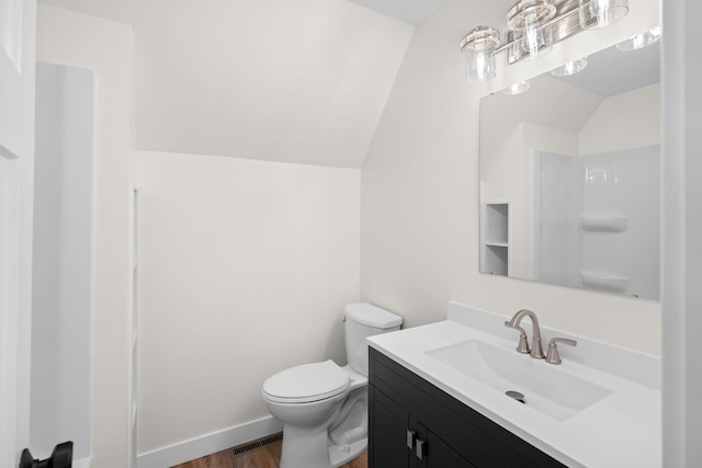 bathroom featuring toilet, vanity, vaulted ceiling, and hardwood / wood-style flooring