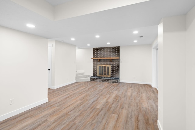 unfurnished living room with light hardwood / wood-style floors and a brick fireplace