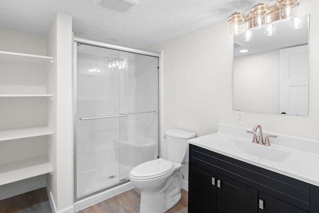 bathroom featuring vanity, hardwood / wood-style flooring, toilet, a textured ceiling, and an enclosed shower