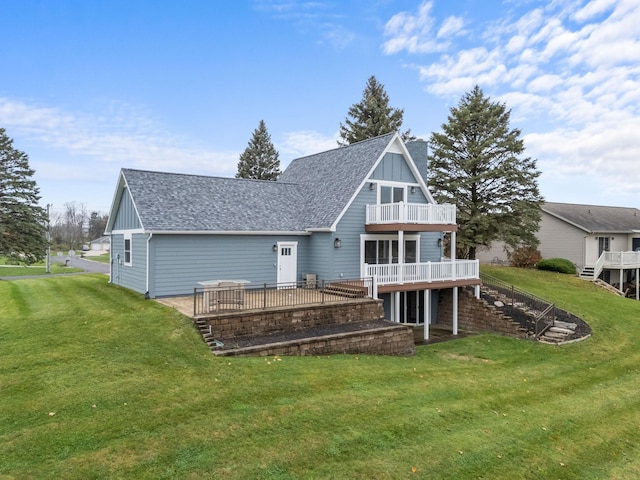 rear view of property featuring a lawn, a balcony, and a deck