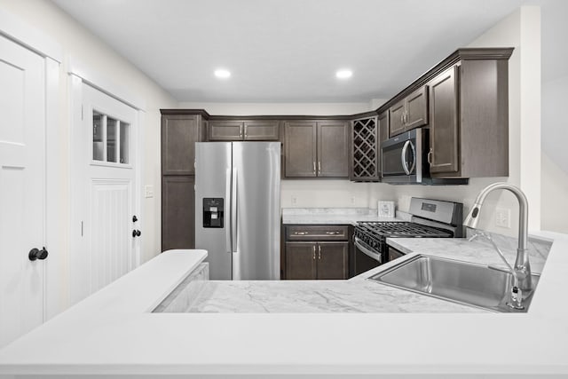 kitchen featuring kitchen peninsula, dark brown cabinets, stainless steel appliances, and sink