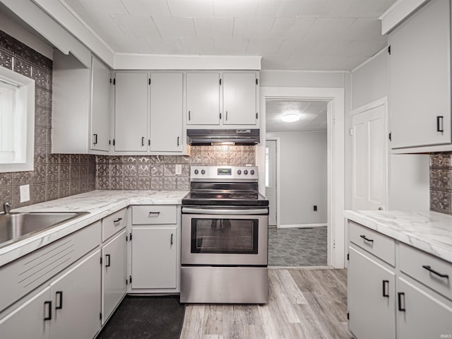 kitchen featuring stainless steel range with electric stovetop, decorative backsplash, light stone countertops, and light wood-type flooring