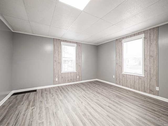 spare room with wood walls, wood-type flooring, and ornamental molding