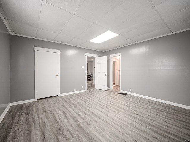 empty room with a paneled ceiling, wood-type flooring, and crown molding