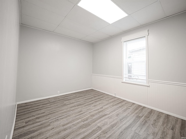 empty room featuring light wood-type flooring and a paneled ceiling