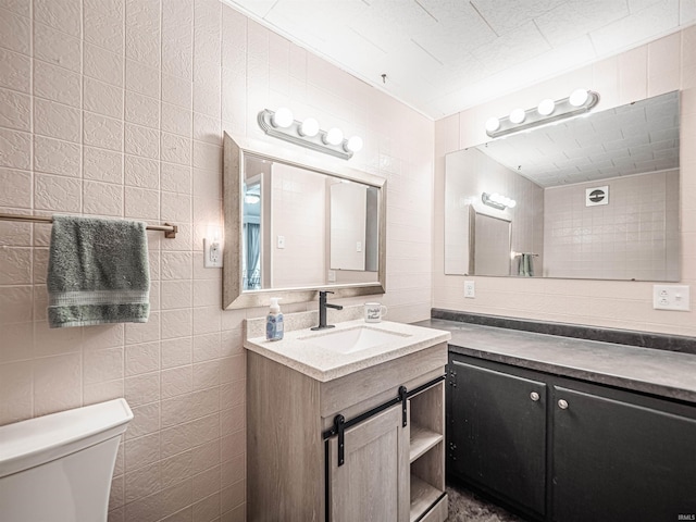 bathroom featuring vanity, toilet, and tile walls