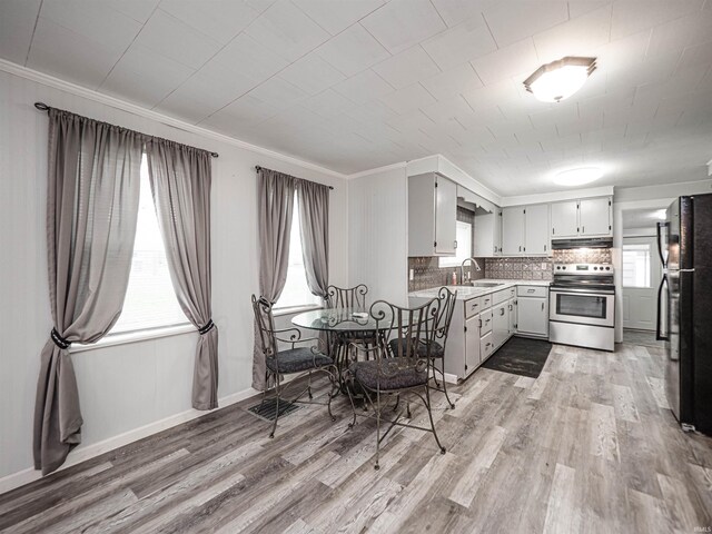 kitchen with stainless steel electric stove, black fridge, crown molding, sink, and light hardwood / wood-style flooring