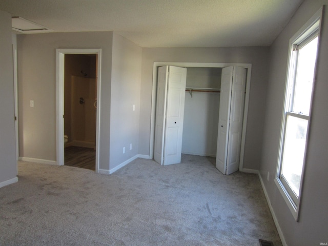 unfurnished bedroom with light carpet, ensuite bath, and multiple windows