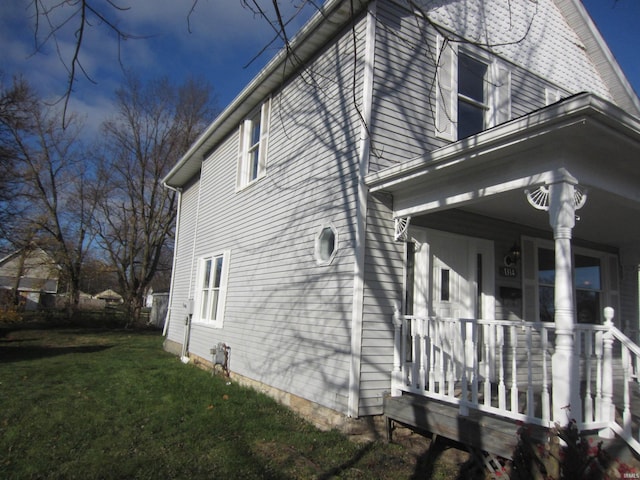 view of home's exterior with covered porch and a yard