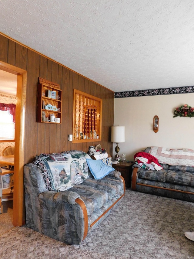 living area featuring carpet, wood walls, and a textured ceiling