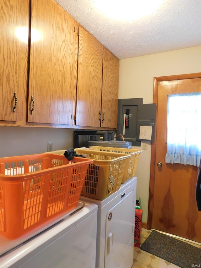 laundry area featuring a textured ceiling, washer and clothes dryer, cabinet space, and electric panel