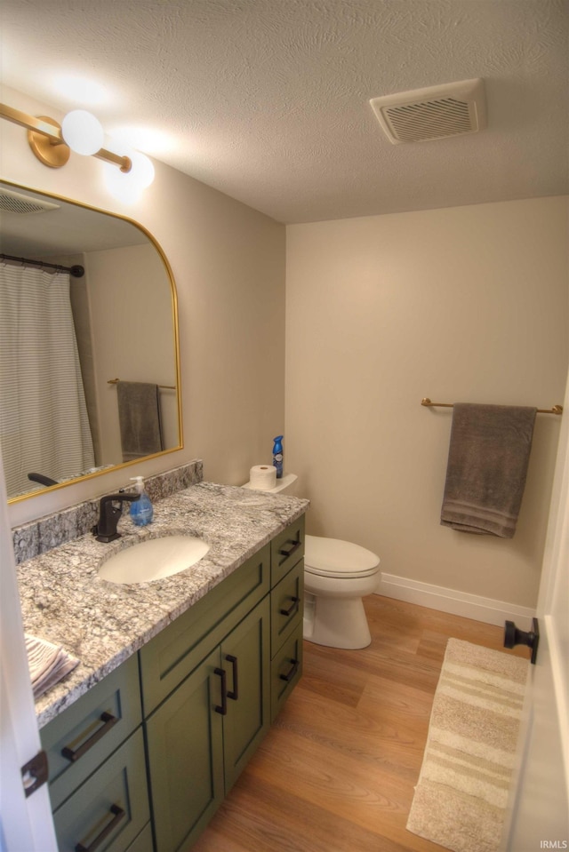 bathroom with vanity, toilet, wood-type flooring, and a textured ceiling