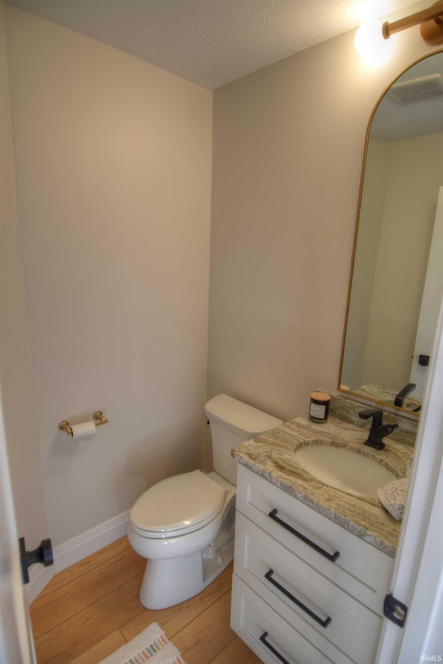 bathroom featuring wood-type flooring, vanity, a textured ceiling, and toilet