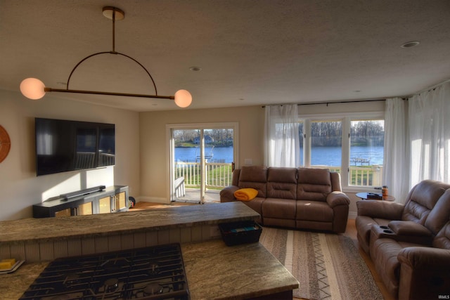 living room featuring plenty of natural light, a water view, and a textured ceiling