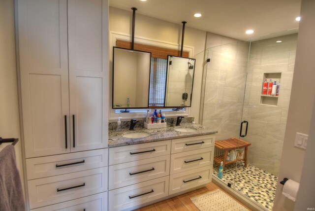 bathroom featuring hardwood / wood-style floors, vanity, and a shower with shower door