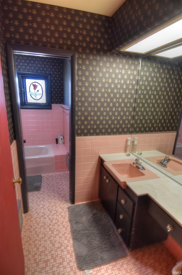 bathroom with vanity, a tub to relax in, and tile walls