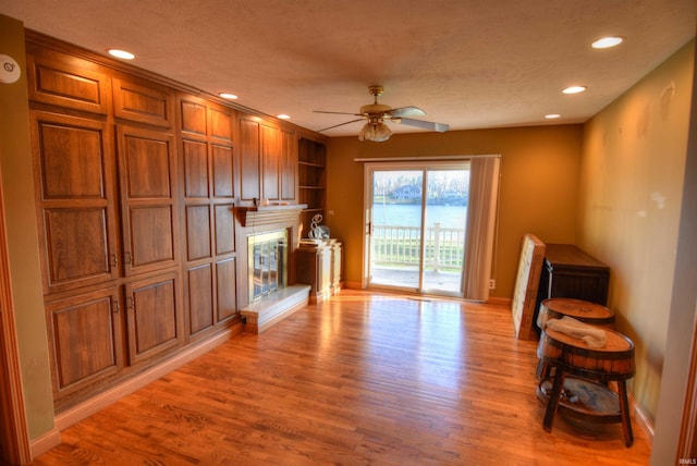 living room with a textured ceiling, light hardwood / wood-style flooring, and ceiling fan