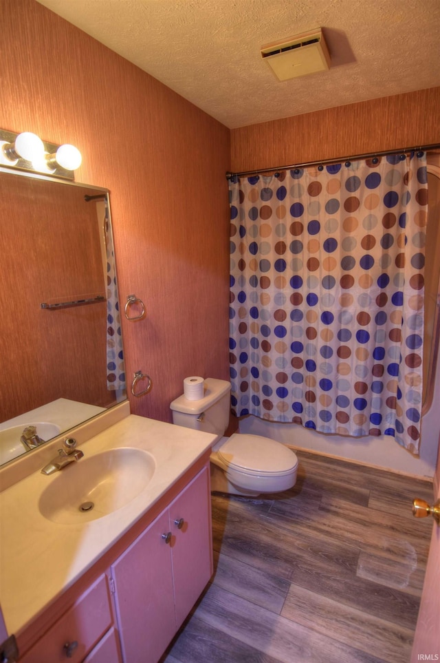 full bathroom with vanity, a textured ceiling, shower / bath combo with shower curtain, hardwood / wood-style floors, and toilet