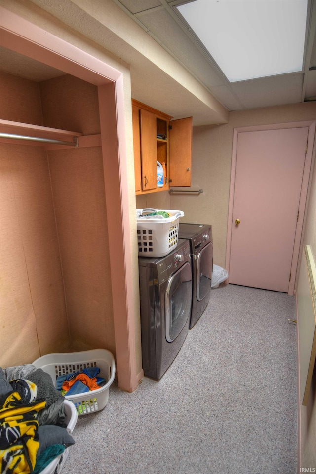 laundry room featuring washer and dryer, light carpet, and cabinets