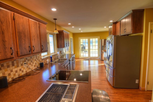 kitchen featuring hanging light fixtures, stainless steel fridge, decorative backsplash, and plenty of natural light