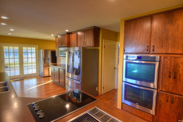 kitchen with french doors, appliances with stainless steel finishes, and light hardwood / wood-style flooring