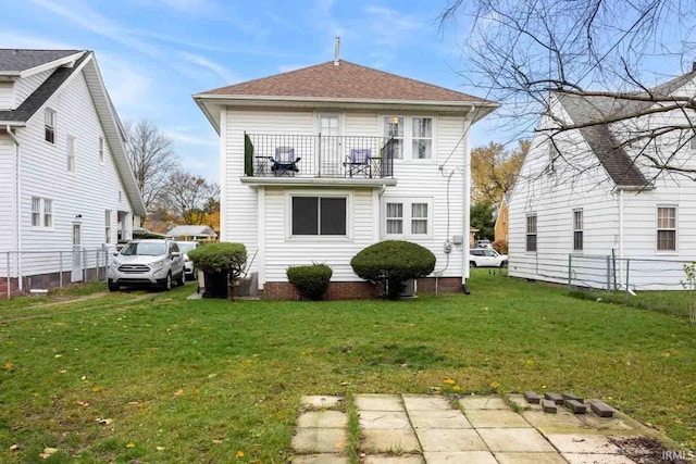 rear view of house with a yard and a balcony