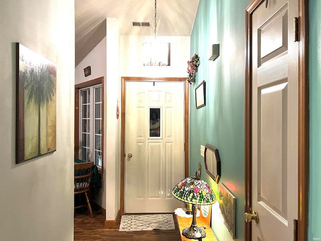 doorway to outside with dark hardwood / wood-style floors, lofted ceiling, and an inviting chandelier