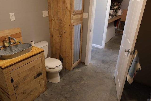 bathroom featuring vanity, concrete flooring, and toilet